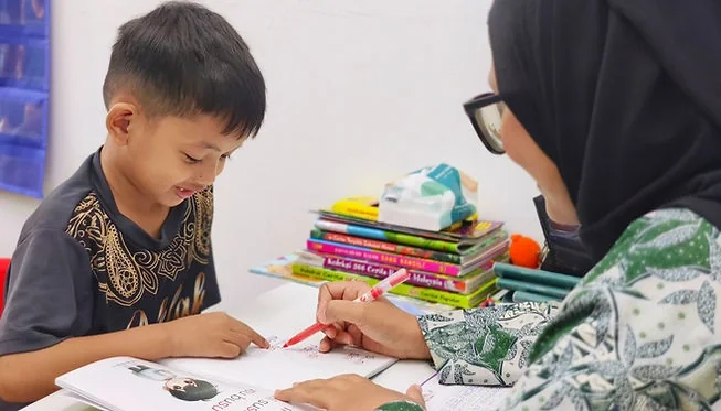 Guru membimbing seorang pelajar membaca secara individu