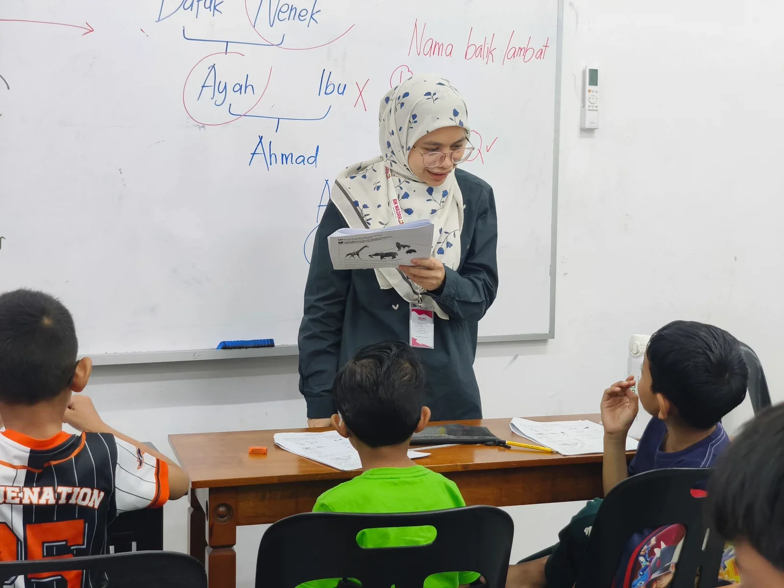 Guru menerangkan pelajaran kepada pelajar di hadapan papan putih